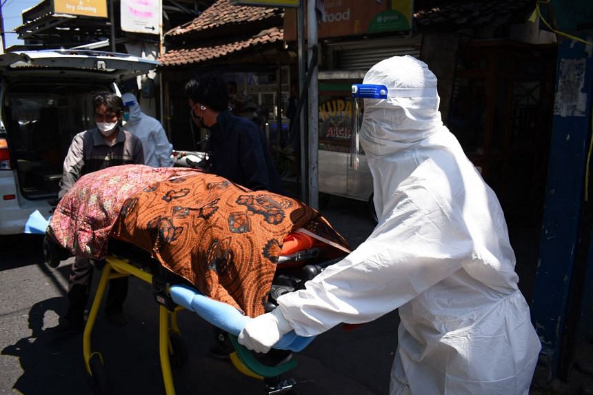 Health workers remove the body of a Covid-19 victim who died while isolating at home in Bandung, Indonesia, on July 28, 2021.