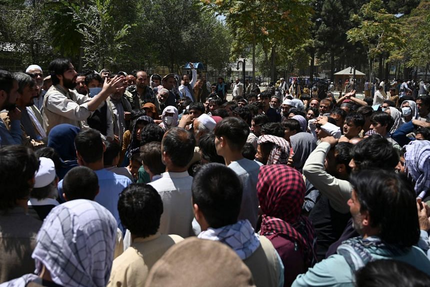 Internally displaced Afghan men, who fled from Kunduz province due to battles between Taleban insurgents and Afghan security forces, gather as they register to receive food at a park in Kabul on Aug 10, 2021.