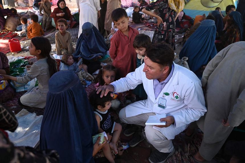 A doctor (right) checks internally displaced children who fled from Afghanistan's Kunduz, Takhar and Baghlan provinces due to battles between Taleban and Afghan security forces, at a  temporary tent in Kabul on Aug 11, 2021.