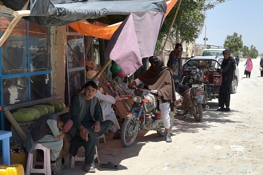 In a photo taken on June 3, 2021, Taleban fighters stand along a road with their motorcycles at a local bazaar in the Andar district of Ghazni province.