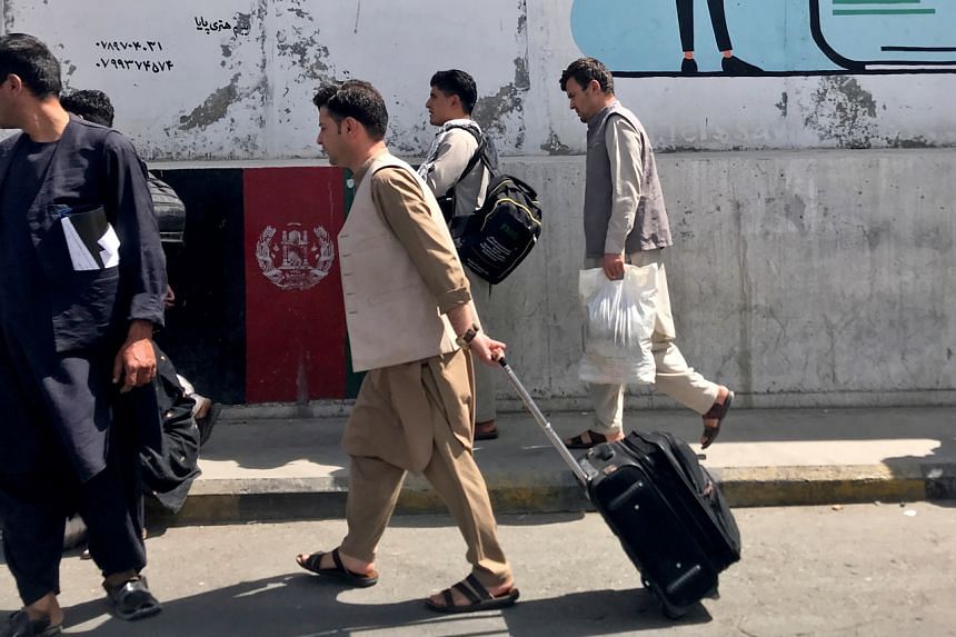 Afghan passengers walk toward the airport in Kabul on Aug 15, 2021.