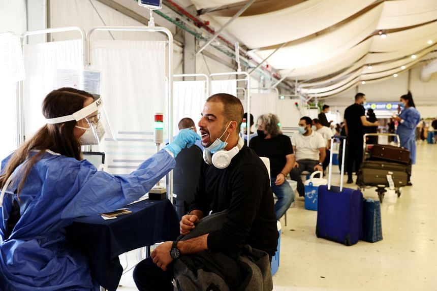 A healthcare worker takes a swab sample from a traveller at the Ben Gurion International Airport in Lod, near Tel Aviv, Israel, on Oct 13.