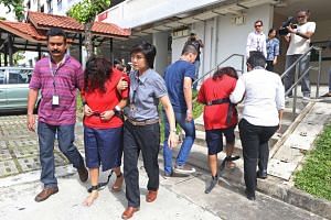 Police officers escorting Gaiyathiri Murugayan (left, in red) and Prema Naraynasamy (right, in red) during investigations, on Aug 3, 2016. 
