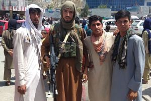 A Taleban fighter with local residents of Pul-e-Khumri after the Afghan city was seized by the group on Wednesday.