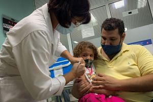 Pedro Montano holds his daughter Roxana, 3, as she is given the Cuban Covid-19 vaccine Soberana Plus as part of a study in Havana on Aug 24, 2021.