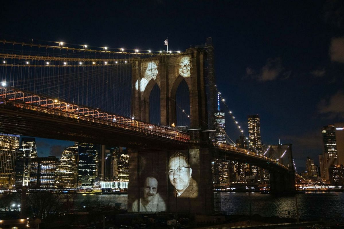 Images of people who died from complications related to the Covid-19 disease are projected on the Brooklyn Bridge during a commemoration ceremony to remember New Yorkers lost during the pandemic in the Brooklyn borough of New York, New York, USA, on 
