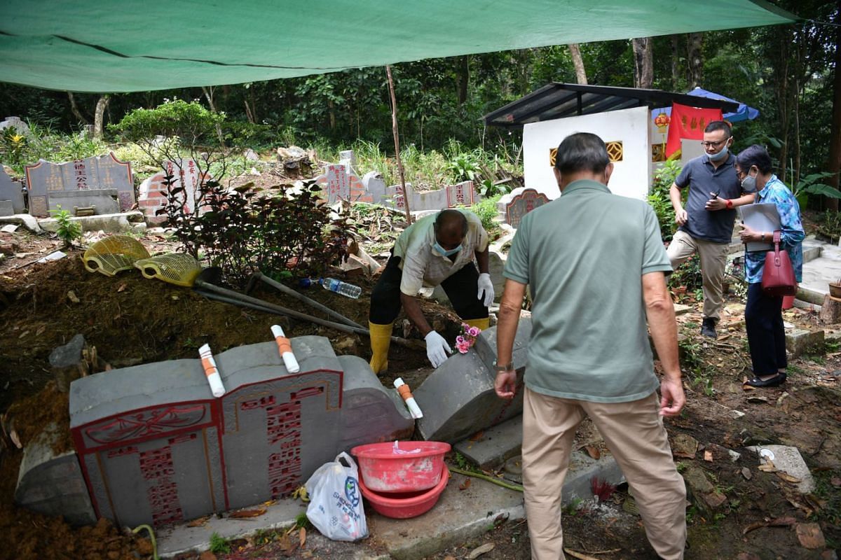 A photo released on March 17, 2021, shows descendants of Ong Chong Chew, a pioneer Chinese merchant, watching the exhumation of his grave in Bukit Brown Cemetery on March 14, 2021. 